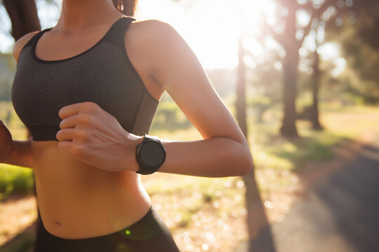 Sporty woman running with smart watch under warm sunlight in scenic park environment for modern fitness lifestyle and health technology marketing
