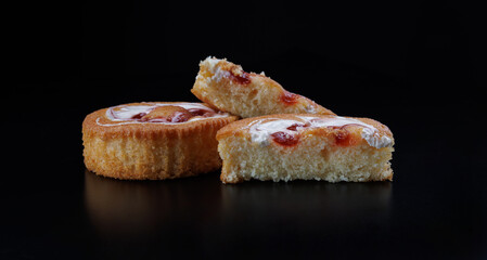 Beautiful sponge cakes whole and cut on a black background.
