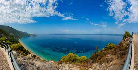 Scenic cliffs near sunny sea shore on a bright clear blue day in Greece. Pefkoulia beach with turquoise water and clear blue sky, Lefkada island, Ionian sea coast