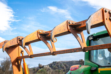 The orange grapple claw of a green tractor, heavy machinery.