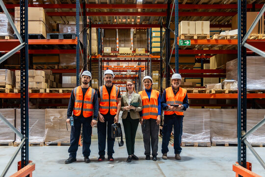 Logistics team workers standing in large distribution warehouse - Powered by Adobe