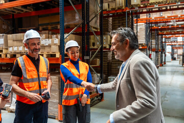 Manager shaking hands with diverse warehouse workers