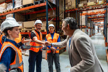 Business manager shaking hands with warehouse workers