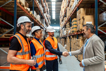 Logistics manager shaking hands with warehouse workers