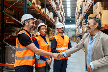 Supply chain manager shaking hand with warehouse workers