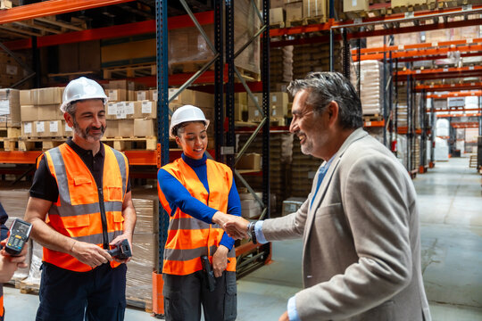 Manager shaking hands with diverse warehouse workers