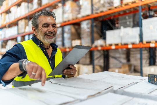 Warehouse worker smiling checking inventory in logistics facility