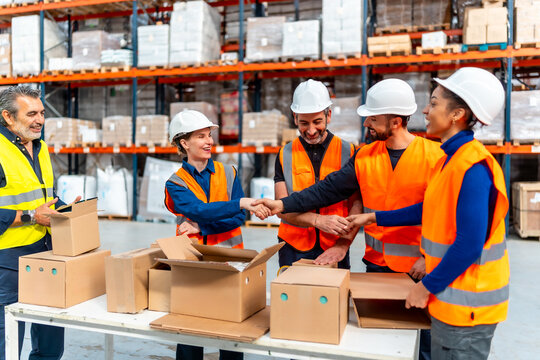 Logistics team workers handshaking in warehouse for successful collaboration