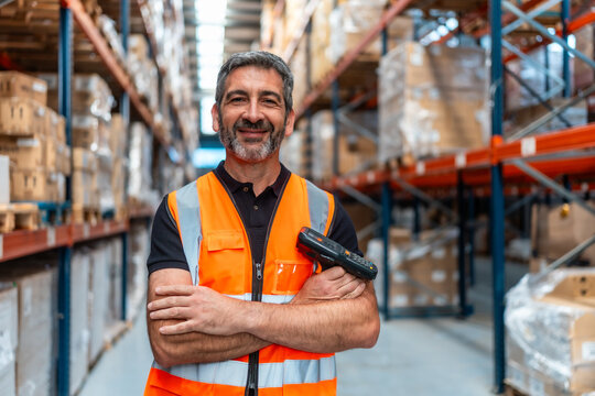 Warehouse worker smiling holding barcode scanner logistics