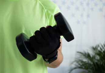 Close up of an unrecognizable man wearing a sports glove while lifting a dumbbell. Concept of strength, training, fitness detail, and active lifestyle