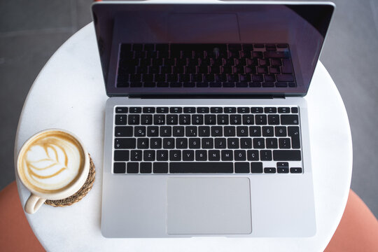 Laptop and coffee cup on white desk.