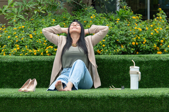 Mulher relaxando descal&ccedil;a em &aacute;rea verde urbana, descanso, pausa no trabalho, bem-estar, lifestyle, natureza, casual, equil&iacute;brio vida profissional e pessoal, sa&uacute;de mental, ver&atilde;o, tranquilidade