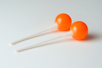 Two vibrant orange lollipops on white sticks, sweet candy treat