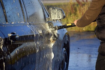 A man washes his car at a self-service station.