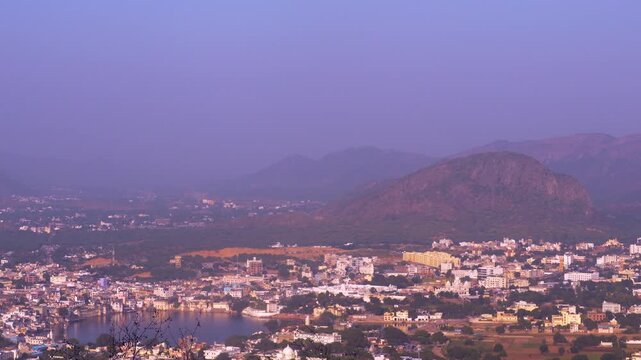 A beautiful cinematic view of Pushkar city resting beside the holy lake and surrounded by the Aravalli range under soft morning light.