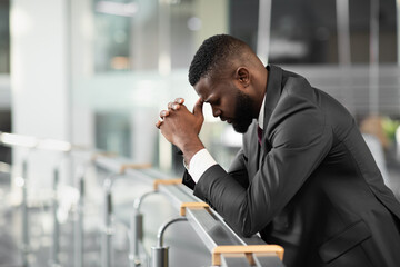 Overwhelmed young black businessman feeling down after business meeting, standing by railing, touching his head, panorama with copy space, side view. Difficulties with business concept © Prostock-studio