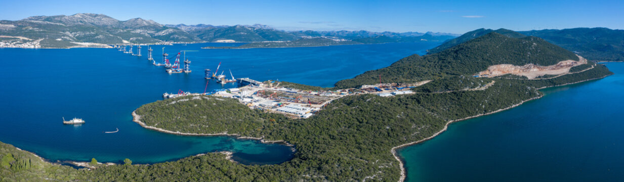Aerial view of the Peljesac Bridge construction site stretching across the calm, deep blue waters, Brijesta, Dubrovnik-Neretva County, Croatia.