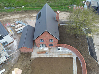 Drone view of a near completed detached family home in rural Britain. The back garden has had top soil laid, ready for grass seeding.