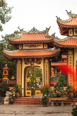 Fototapeta premium asian-style carved gate with roof at a buddhist temple, staircase leading to it and flower pots on the sides