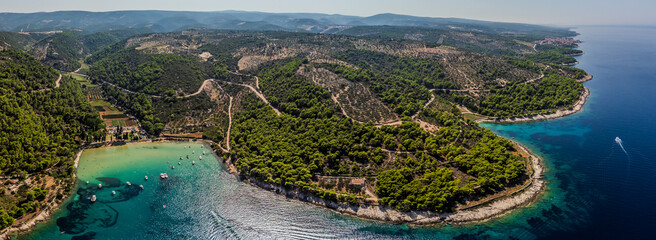 Aerial view of boats bobbing gently in the turquoise bay against the backdrop of lush forests and rugged coastline, Brac, Split-Dalmatia County, Croatia.