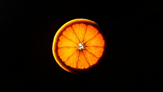 Luminous backlit orange fruit slice with glowing translucent segments