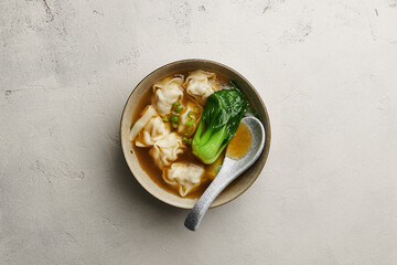 Chinese wonton soup on light concrete background, top view