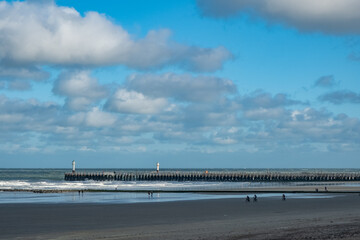 Serene beach landscape, Peaceful coastal scene with sky and surf, Calm shoreline with distant figures and scattered