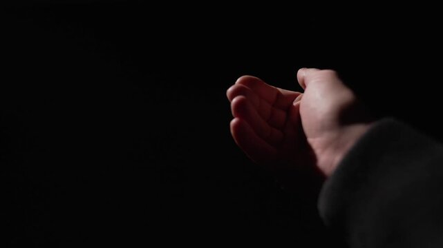 POV, close-up first person view stranger makes gesture of money with fingers on black background. Close-up of man's hands gesturing to suggest bribe. The man demands payment and returns the debt.