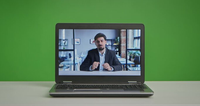 A laptop displaying a live streaming session in a professional studio setting with green screen background.