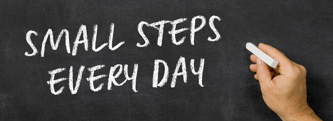 Naklejka premium Text written on a blackboard - Small steps every day