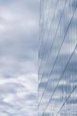 Obraz premium Vertical low angle detail view of glassed skyscraper and cloudy sky reflecting in its facade, Vienna, Austria 