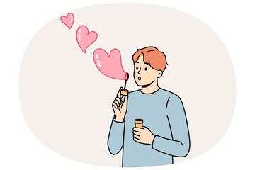Romantic man uses heart-shaped soap bubbles to show love and kindness to people around him. Concept of romantic mood and desire to enter into serious relationship or marry girl you like