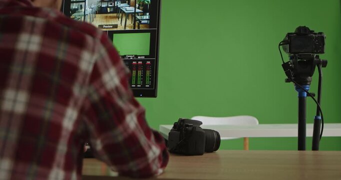 A modern live streaming studio featuring a presenter in front of a green screen with advanced equipment. A man in a suit presents information or news. Ideal for media production.