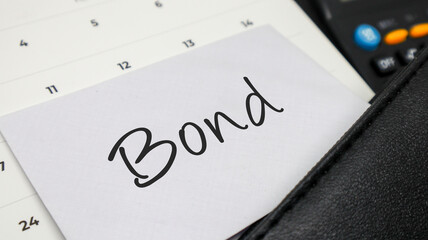 A white envelope with Bond written on it, tucked into a calendar alongside a calculator, symbolizing financial concept.