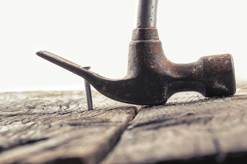 A rusty claw hammer pulls a nail from weathered wooden planks, showcasing classic construction...