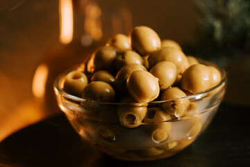 Freshly harvested green olives showcased in a clear glass bowl with warm lighting