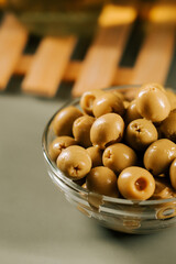 Fresh green olives in a clear bowl on a wooden surface