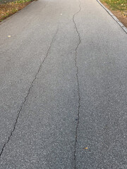 Fototapeta premium Cracked asphalt surface with visible damage lines. Urban decay, infrastructure wear, and passage of time.