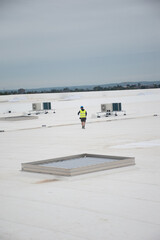 Air conditioning technician inspecting an HVAC system on a rooftop , checking equipment performance and taking maintenance measurements.