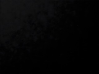 A black, grainy background with a consistent texture, reminiscent of a dark, fine-grained sandpaper or a closely woven fabric under low lighting