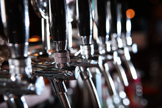 Beer taps in pub. Concept of alcohol. Vintage style. Craft beer. Bar table. Shiny steel cranes. Nobody. Selective focus.