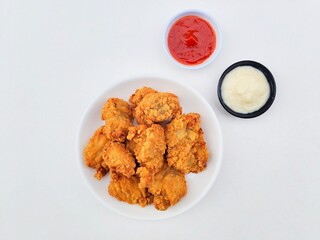 Crispy and crunchy fried chicken in a white plate and mayonnaise sauce in a small black bowl and...