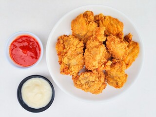 Crispy and crunchy fried chicken in a white plate and mayonnaise sauce in a small black bowl and...