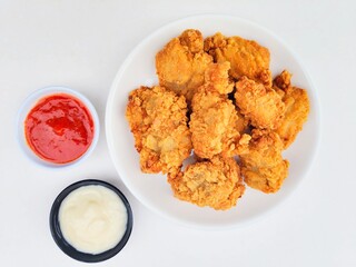 Crispy and crunchy fried chicken in a white plate and mayonnaise sauce in a small black bowl and...