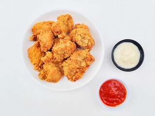 Crispy and crunchy fried chicken in a white plate and mayonnaise sauce in a small black bowl and...