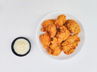 Crispy and crunchy fried chicken in a white plate and mayonnaise sauce in a small black bowl on a...