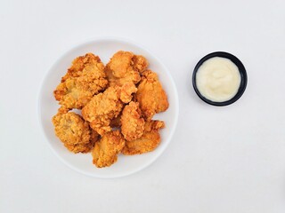 Crispy and crunchy fried chicken in a white plate and mayonnaise sauce in a small black bowl on a...