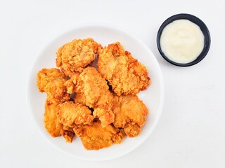Crispy and crunchy fried chicken in a white plate and mayonnaise sauce in a small black bowl on a...