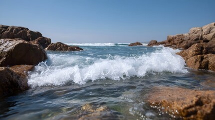 A dynamic ocean wave breaks against weathered rocks on a clear sunny day showcasing the raw power of nature at the coast