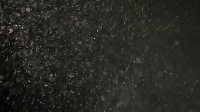 Soft pollen and dust particles floating in the air, illuminated by cold light beams, creating dreamy abstract bokeh on a dark background. 4K macro footage with gentle motion and selective focus.